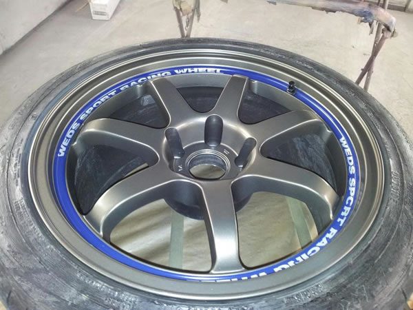 A refurbished grey alloy wheel with a blue rim stripe
