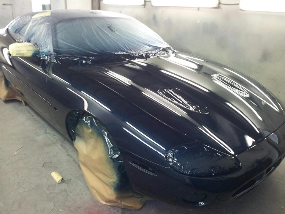 Gloss black Jaguar bonnet in the booth reflecting the strip lights