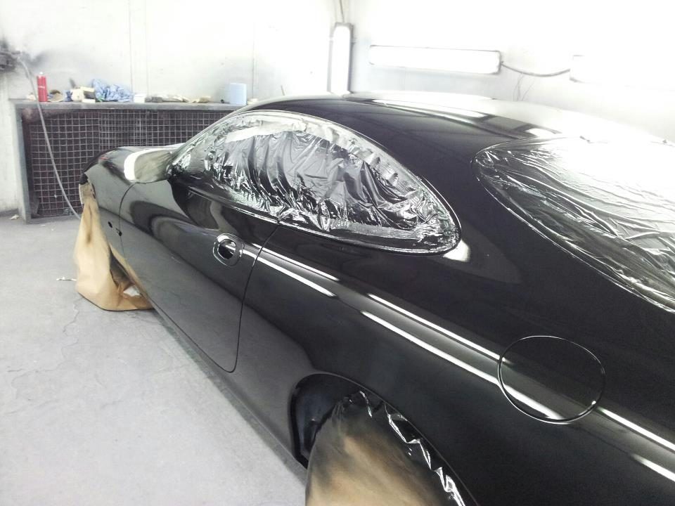 A black Jaguar freshly painted in the Perfect Paint spray booth, windows still masked