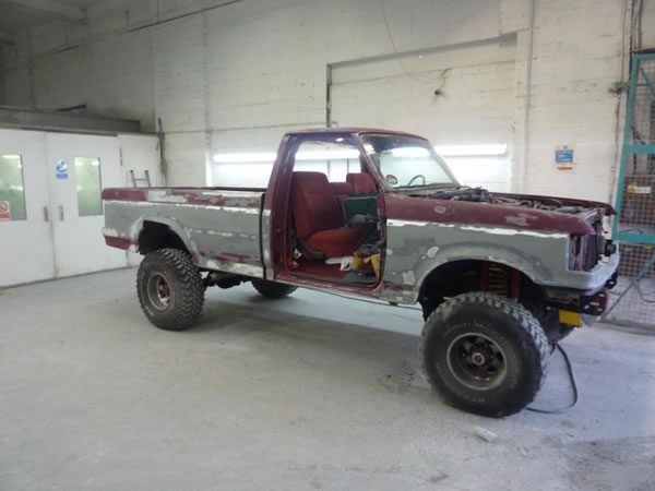 The pickup stripped back in the workshop, bare metal showing through faded red